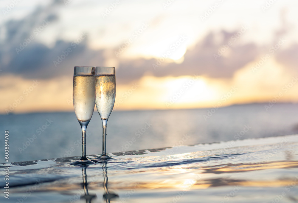 Two glasses of champagne on the side of the infinity pool against the backdrop of a sunset in the Maldives - obrazy, fototapety, plakaty 