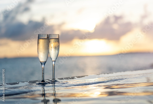 Print op canvas Two glasses of champagne on the side of the infinity pool against the backdrop o