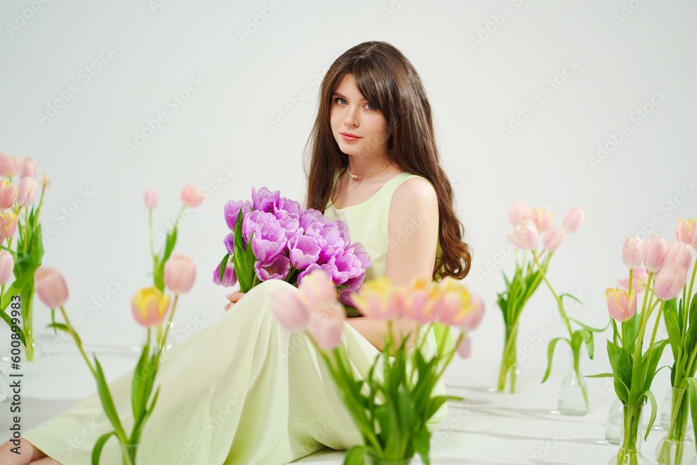 a woman in a delicate dress sits on the floor with bouquet surrounded by tulips 