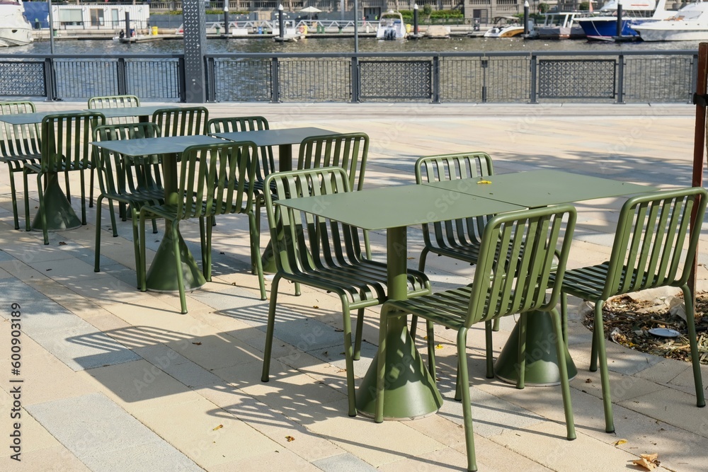 Modern metal tables and chairs are khaki color. Empty outdoor cafe. Urban street furniture