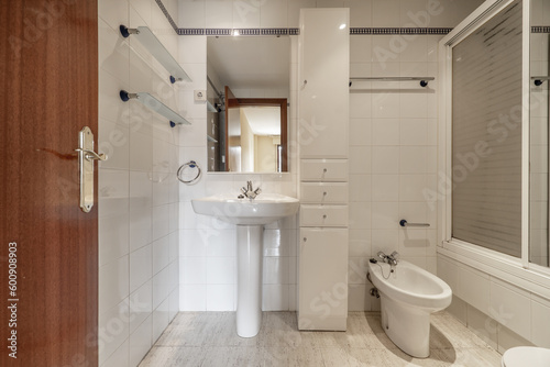 A complete bathroom with showers with screens, white column furniture