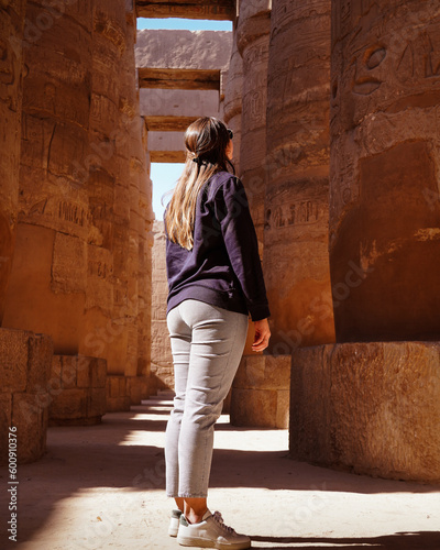 Tourist woman in Karnak Temple staring at the ancient columns with hieroglyphs, Luxor, Egypt.