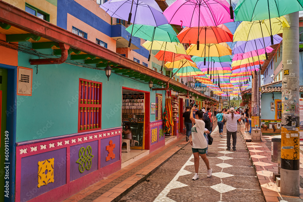 Obraz premium Old street in Guatapé Colombia with colorful umbrella's overhead with people taking pictures 
