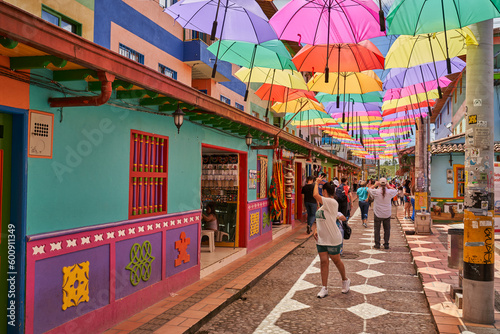Old street in Guatapé Colombia with colorful umbrella's overhead with people taking pictures 