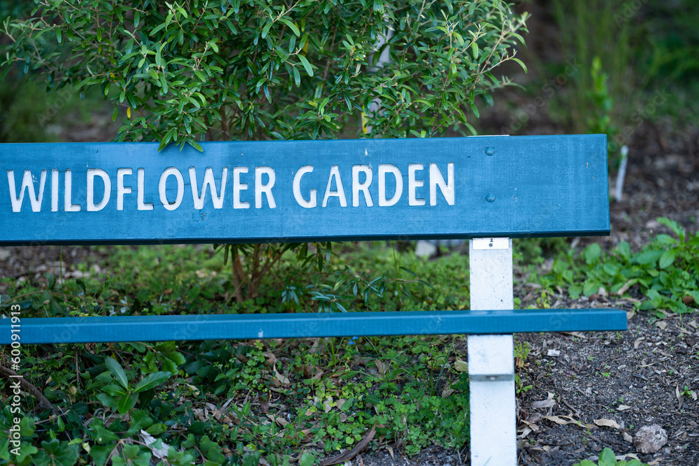 wooden seat, wooden garden sign saying to garden, next to a path in a forest In Australia 