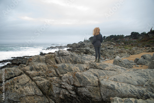 blond woman on the black rocks of isla negra 