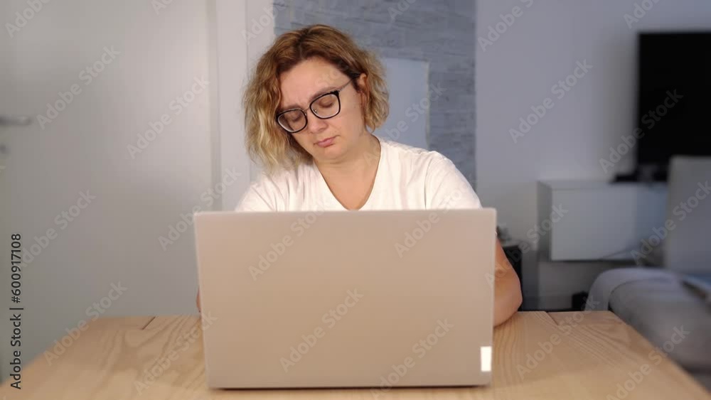 Sleepy blonde in glasses naps looking at white laptop screen Sleepy blonde in glasses naps looking at white laptop screen