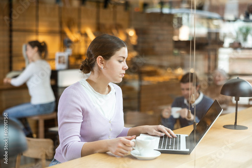 Confident female cafe customer enjoying peace and quiet while working on laptop