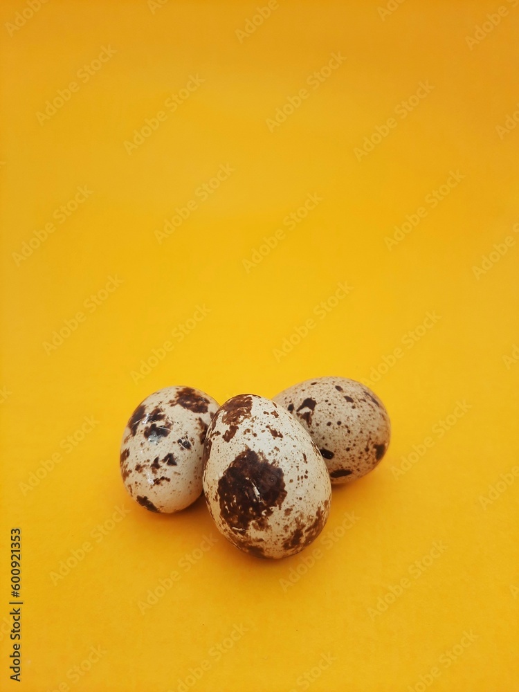 Fototapeta premium three quail eggs isolated on yellow background