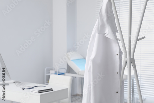 White doctor's gown hanging on rack in clinic. Space for text © New Africa
