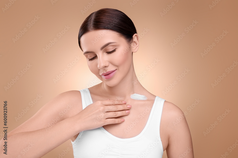 Beautiful woman with smear of body cream on her neck against light brown background Beautiful woman with smear of body cream on her neck against light brown background