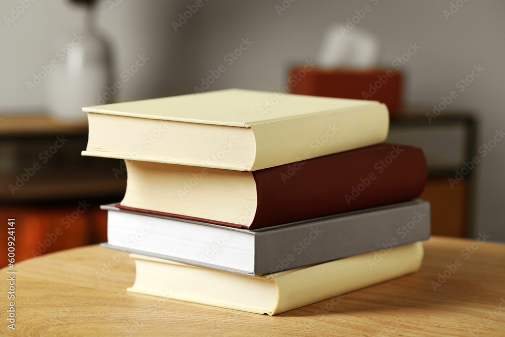 Many books stacked on wooden table indoors Many books stacked on wooden table indoors