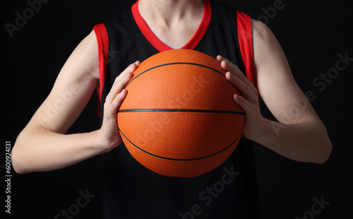 Boy with basketball ball on black background, closeup