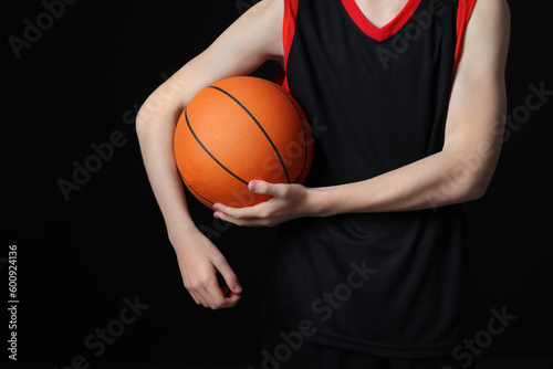 Boy with basketball ball on black background, closeup © New Africa