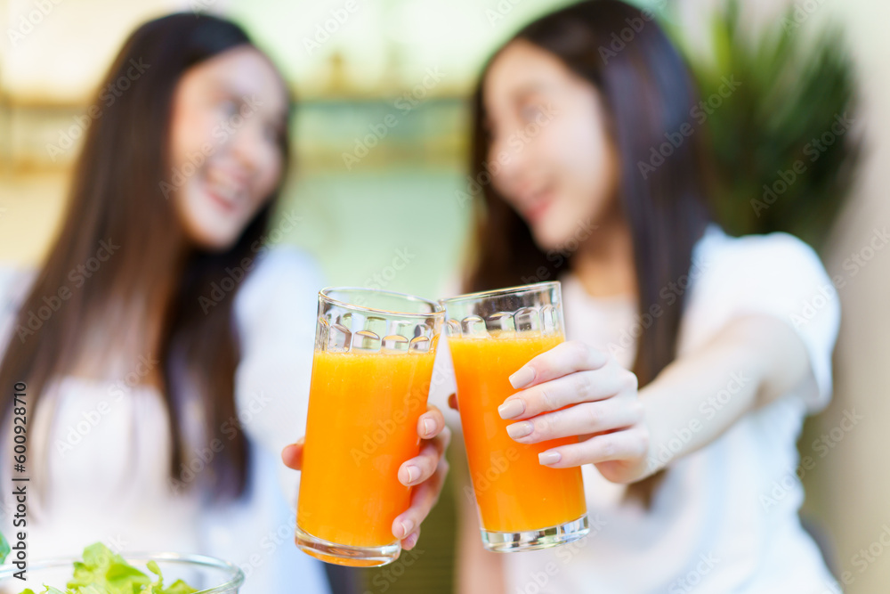 Asian women enjoying eating a breakfast and drinking organic orange juice together in the dining room. Asian women enjoying eating a breakfast and drinking organic orange juice together in the dining room.