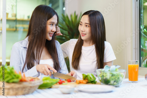 Asian women enjoying eating a breakfast and drinking organic orange juice together in the dining room. 