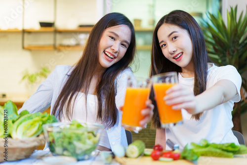Asian women enjoying eating a breakfast and drinking organic orange juice together in the dining room. 