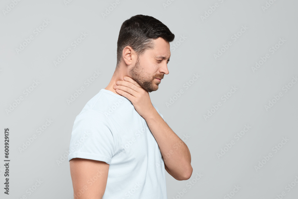 Man suffering from sore throat on light gray background Man suffering from sore throat on light gray background