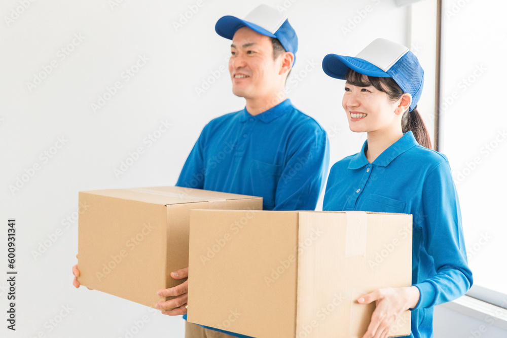 段ボールを持つ引越し業者・配達員の男女（引越し・配達・軽貨物ドライバー・宅配・配達員・宅急便）
