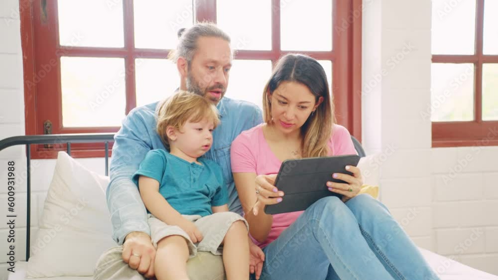 Caucasian attractive couple using tablet with young baby boy on bed. Caucasian attractive couple using tablet with young baby boy on bed.