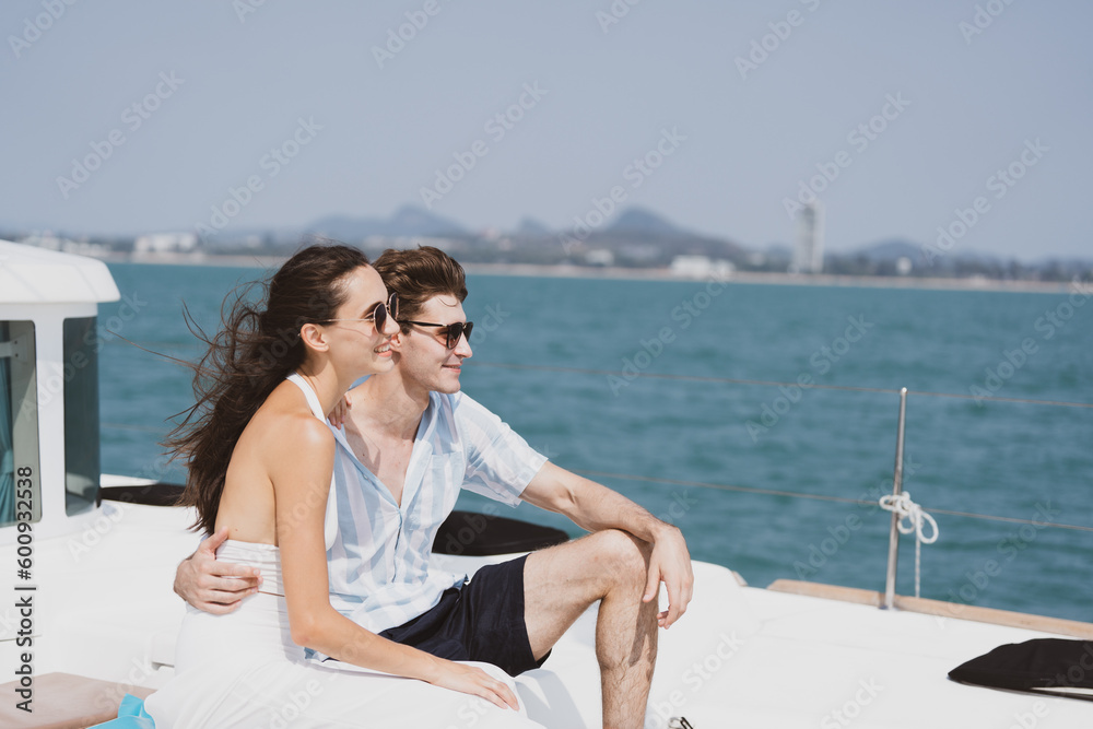 Caucasian couple who man and woman relax fun with luxury party drinking champagne by talking together while catamaran yacht boat sailing. Happy and enjoy outdoor lifestyle on summer vacation travel