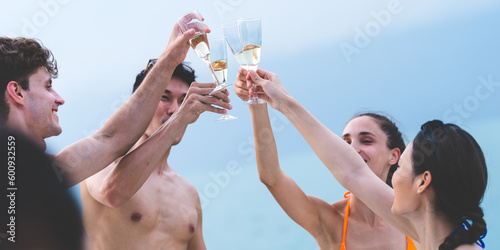 Friends group drink a champagne at outdoor party on yacht. Attractive young men and women hanging out, happy fun to celebrating holiday vacation trip on catamaran sailing boat, Summer relaxation time © chokniti