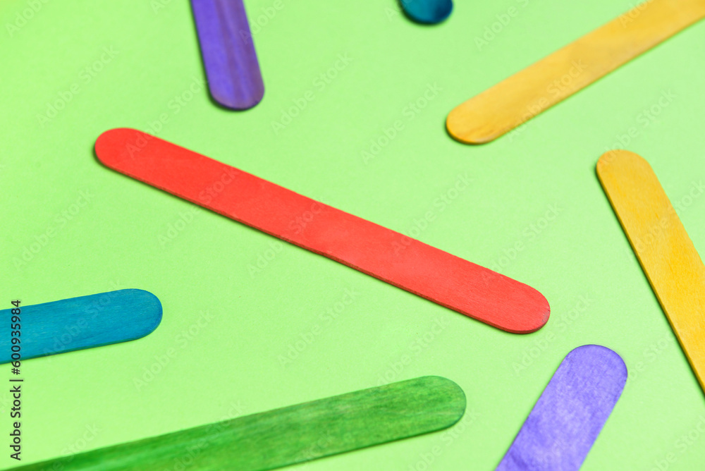 Colorful ice cream sticks on green background, closeup Colorful ice cream sticks on green background, closeup