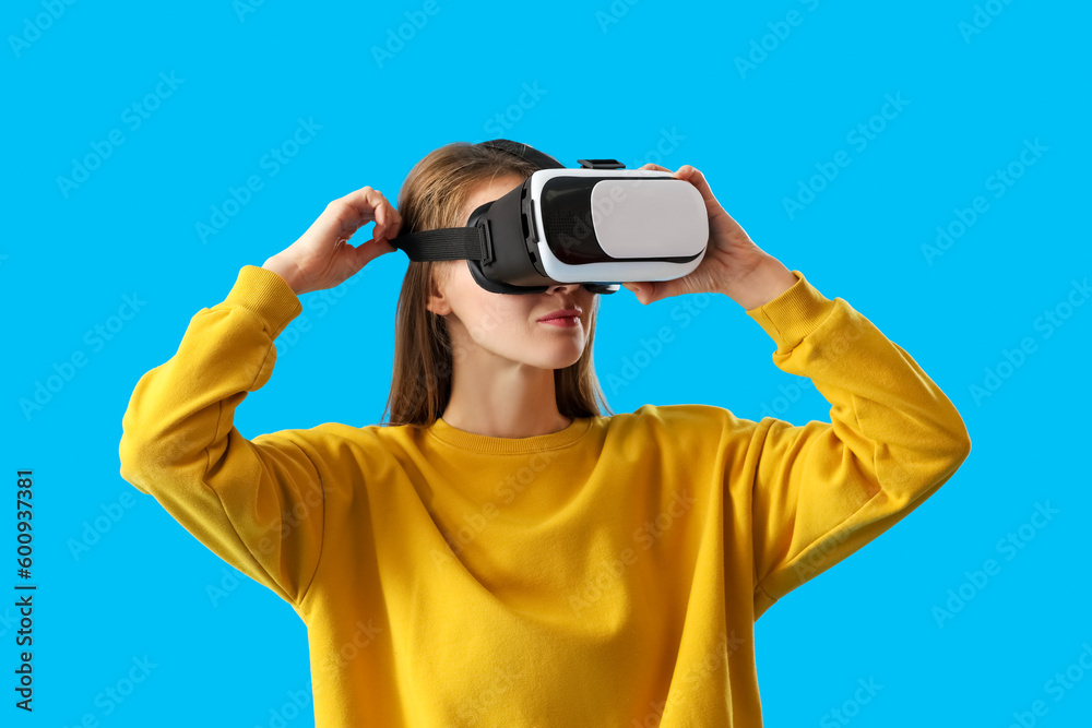 Pretty young woman in VR glasses on blue background Pretty young woman in VR glasses on blue background
