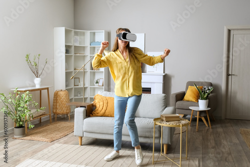 Pretty young woman in VR glasses at home © Pixel-Shot