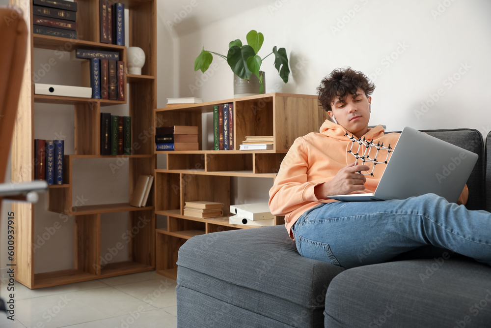 Male student with molecular model and laptop at home