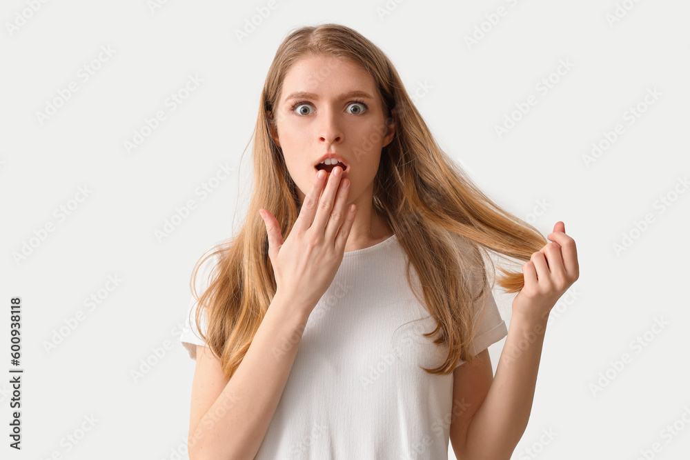 Shocked young woman with hair loss problem on light background Shocked young woman with hair loss problem on light background