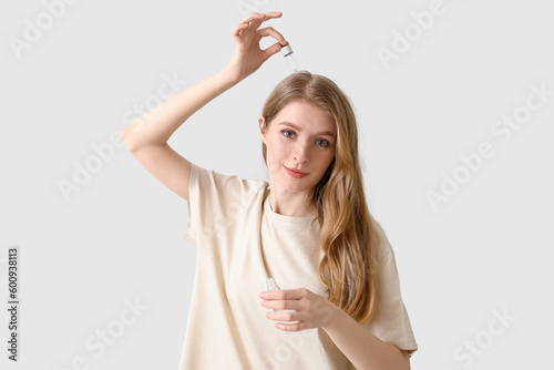 Young woman using serum for...