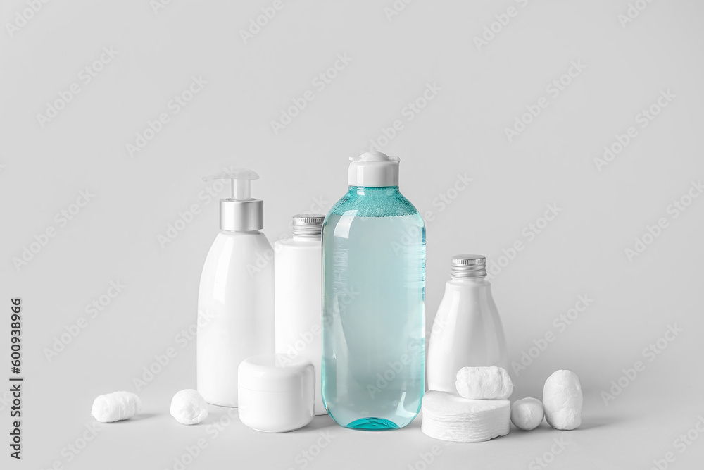 Micellar water with cosmetic products, cotton balls and pads on light background Micellar water with cosmetic products, cotton balls and pads on light background