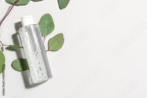 Bottle of micellar water with eucalyptus branches on light background photo