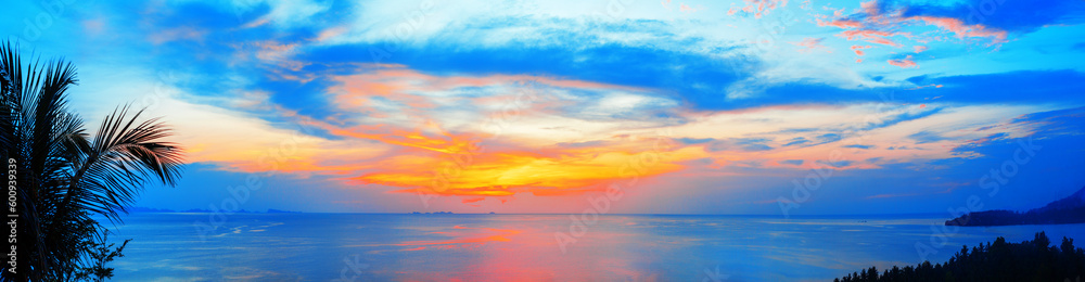 Beautiful sea sunset landscape, ocean sunrise, tropical island beach dawn, palm tree leaves silhouette, blue water, colorful red pink orange yellow sky clouds, sun reflection, summer holidays vacation