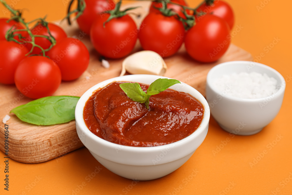 Bowl of tomato sauce and board with ingredients on orange background, closeup Bowl of tomato sauce and board with ingredients on orange background, closeup