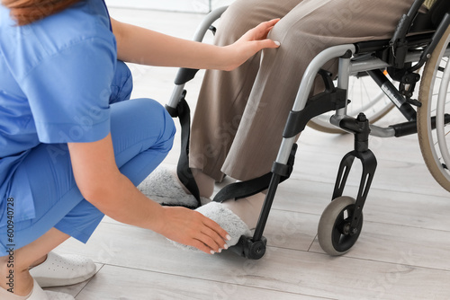 Young caregiver with senior woman in wheelchair at home