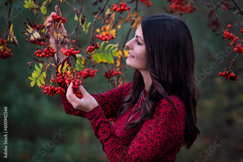 Young smiling woman picking red berries on the tree