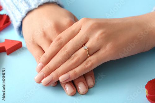 Woman with engagement ring on blue background  closeup
