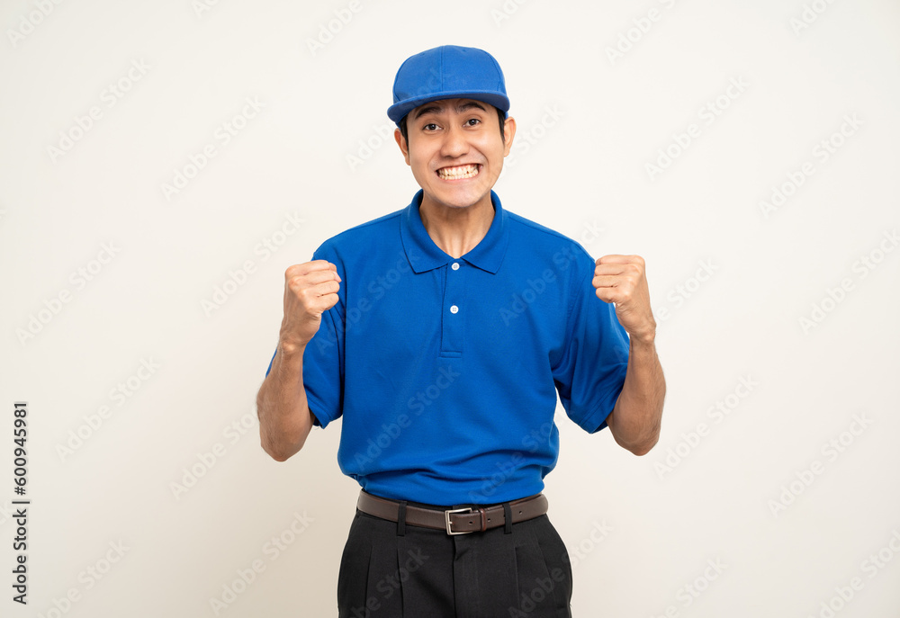 Happy delivery asian man in blue uniform standing on isolated white background. Smiling male service worker. Delivery courier and shipping service.