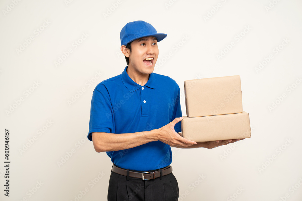 Asian man in blue uniform standing holding box parcel cardboard and smartphone on isolated white background. Male service worker with cell phone. Delivery courier shipping service Asian man in blue uniform standing holding box parcel cardboard and smartphone on isolated white background. Male service worker with cell phone. Delivery courier shipping service