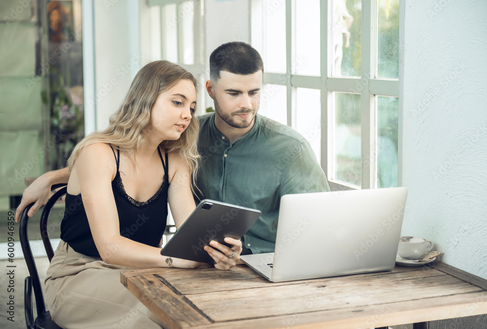 business couple Cheerful woman using laptop in coffee shop Young businessman and happy girlfriend smiling while working together Two young businessmen sit together at the table.