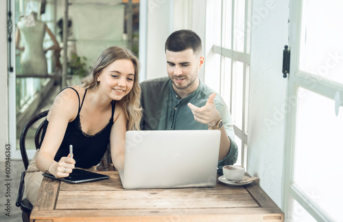 business couple Cheerful woman using laptop in coffee shop Young businessman and happy girlfriend smiling while working together Two young businessmen sit together at the table.