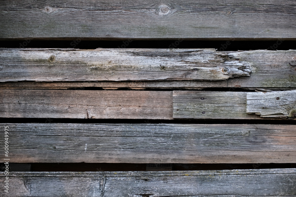 Weathered old wooden wall detail. Simple gray boards with knotholes and coarse grain nailed together. Outdoor. Backgrounds. Weathered old wooden wall detail. Simple gray boards with knotholes and coarse grain nailed together. Outdoor. Backgrounds.