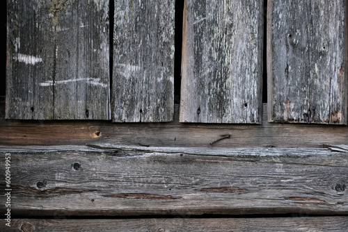 Weathered old wooden wall detail. Simple gray boards with knotholes and coarse grain nailed together. Outdoor. Backgrounds.
