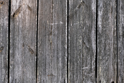 Weathered old wooden wall detail. Simple gray boards with knotholes and coarse grain nailed together. Outdoor. Backgrounds.