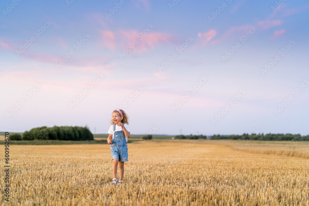 a little blonde curly girl running in a wheat field, the concept of human freedom