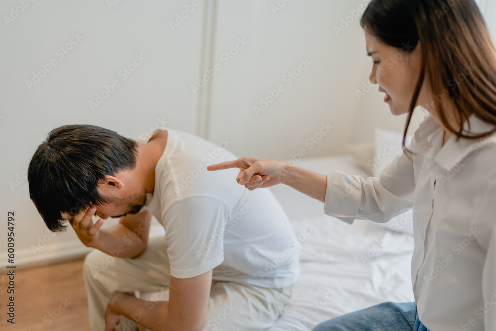 Domestic Violence, Asian Wife Threatening husband, Scared family leader Embracing his While Sitting Together On bed. Domestic Violence, Asian Wife Threatening husband, Scared family leader Embracing his While Sitting Together On bed.