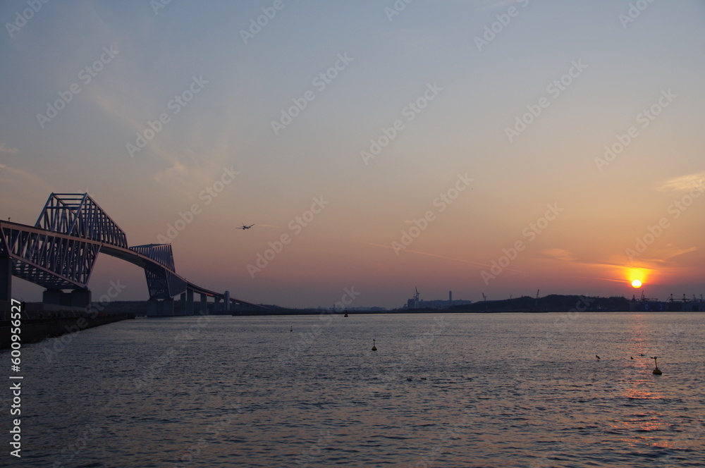 Obraz premium 夕暮れに橋の上を飛ぶ飛行機