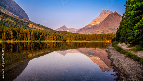Mt. Wilbur reflection in the smooth surface of Fishercap Lake at sunrise in the Many Glaciers area of Glacier National Park, Montana, USA photo